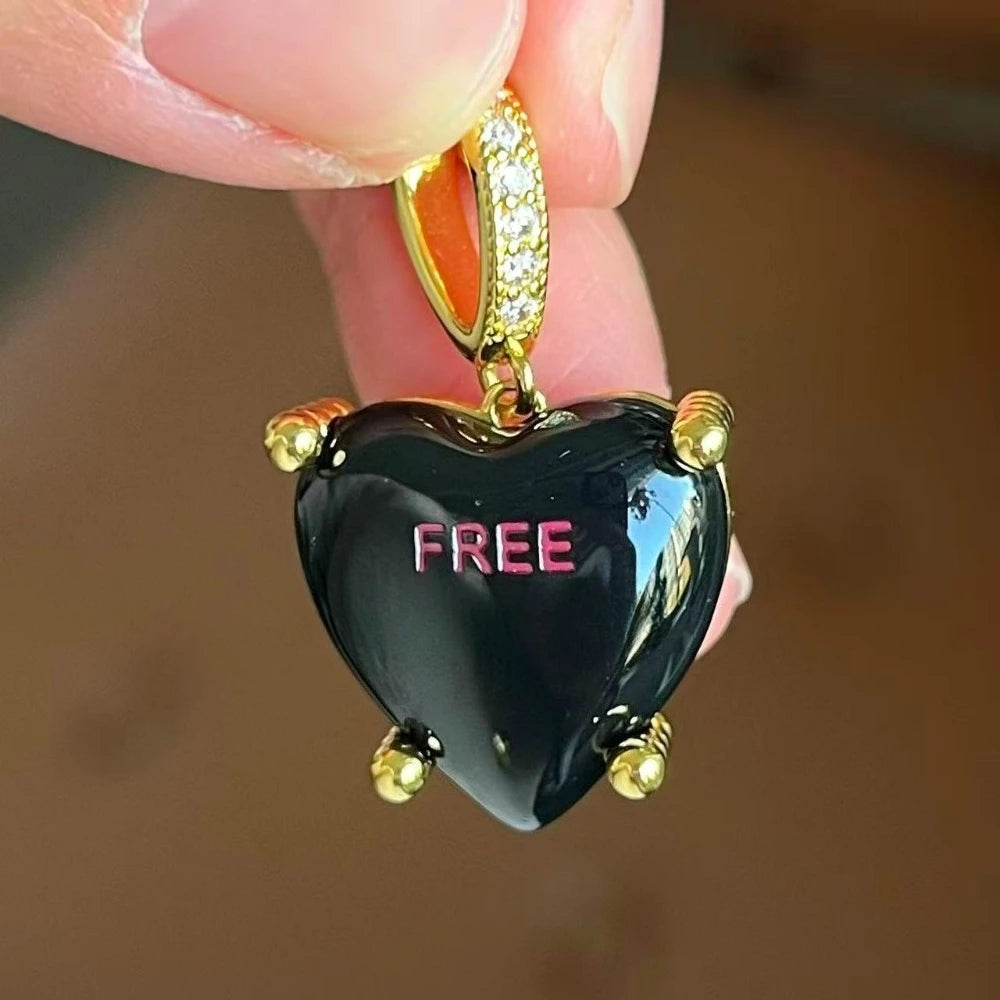 Heart-shaped pendant with 'FREE' text held by a hand against a blurred background